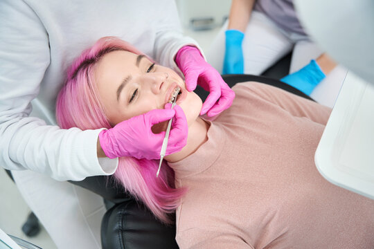 Orthodontist examines a female patient in a dental chair