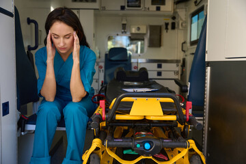 Woman from emergency medical team sits with head in hands