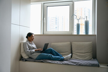 Pretty elegant business woman is typing message on laptop in her flat