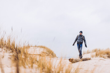 Man trekking on dunes by the sea at autumn