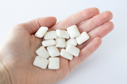 Helpful sugar-free xylitol gum for teeth in a woman's hand on a white background