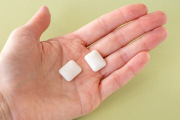 Healthy sugar-free xylitol gum for teeth in a female's hand on a green background
