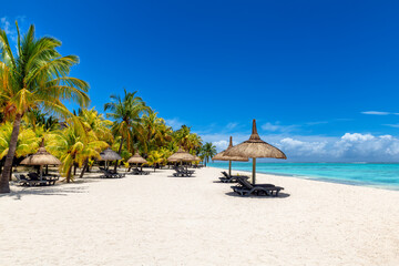 Tropical vacations beach with palm trees and straw umbrellas and tropical sea in Paradise Mauritius island.	