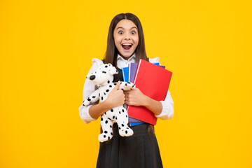 Schoolgirl 12, 13, 14 years old with toy. School children cuddling favorite toys on yellow...