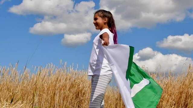 Happy girl holding Pakistan flag dancing outdoor under sunny sky.