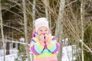 cute cheerful toddler girl in a snowy forest, bright spring sun, snow