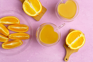 Fresh orange juice in glass and oranges on a pink colored background. Top view.