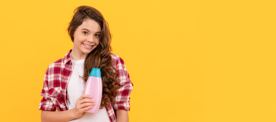 happy teen girl with long curly hair hold shampoo bottle, cosmetic. Banner of child girl hair care,...