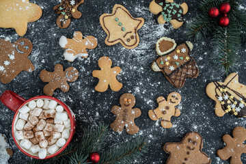 Homemade gingerbread Christmas cookies with icing or frosting, covered in flour. Hot chocolate cocoa with marshmallows. Various decorated gingerbreads. Holiday Season winter flat lay composition.
