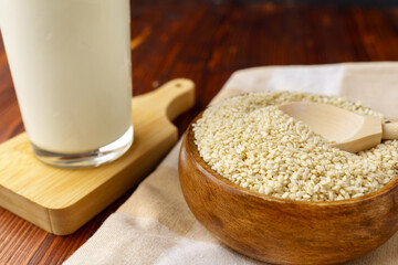 Sesame seed milk in a glass. White sesame seeds on a table. Dairy Alternative.