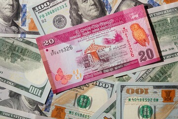 Fototapeta na wymiar 20 Sri Lankan rupees on a background of 100 dollar bills