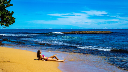Fototapeta na wymiar beautiful girl in a bikini lies on the sand on a Caribbean beach in Costa Rica; sunbathing on a paradise beach by the Caribbean sea, beach vacation in tropical Costa Rica