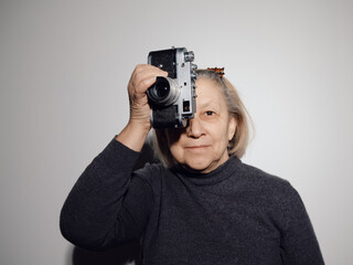 a grandmother with a retro film camera looks into the camera and takes a shot