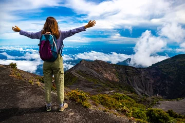 Fotobehang girl with backpack standing on top of volcano irazu in Costa Rica, volcanic landscape of Irazú Volcano National Park, massive volcano in clouds in Costa Rican mountains © Jakub