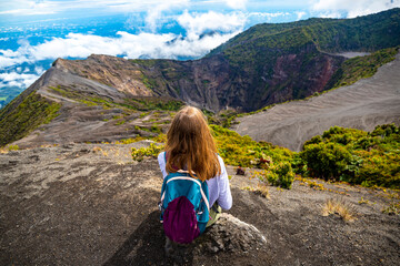 girl with backpack sits on top of volcano irazu in Costa Rica, volcanic landscape of Irazú Volcano...