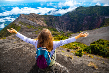 girl with backpack sits on top of volcano irazu in Costa Rica, volcanic landscape of Irazú Volcano...