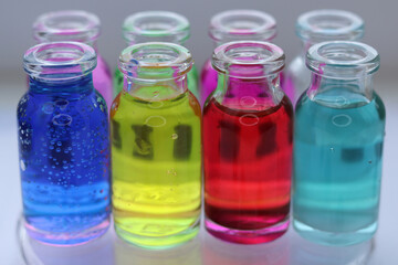 Fototapeta na wymiar Colored aqueous solutions of various indicator dyes in glass jars for chemical reactions.