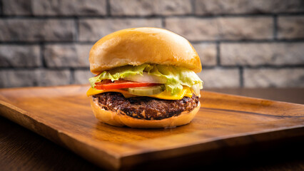 Volcano burger with cucumber, tomato, cheese, onion isolated on wooden board side view on table...
