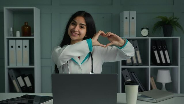 Caring sincere young woman arabian latina cardiologist medical student cardiology medicine doctor make love symbol heart organ shape demonstrate human generosity care support charity donation concept