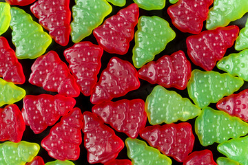 Christmas tree-shaped red and green gummy jelly candy on a table. Top view, background.