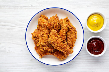 Homemade Chicken Strips with Mustard and BBQ on a Plate, top view. Flat lay, overhead, from above.