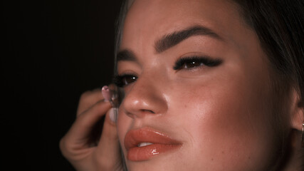 Makeup artist adjusts model's eyelashes before shooting