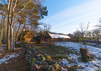 Fototapeta na wymiar Old log farm houses in a park a pale sun winter day in Stockholm