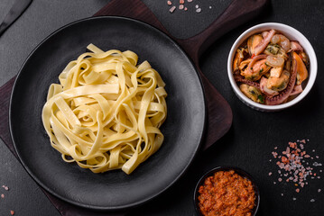 Delicious fresh pasta with pesto sauce and seafood on a black plate