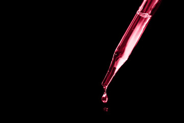 a drop of oil falling from a glass pipette. cosmetology, chemistry, perfumery. macro photo close...