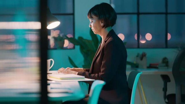 Business, woman and computer at night while reading an email with good news about corporate project. Late, overtime and smiling businesswoman typing successful online review or proposal