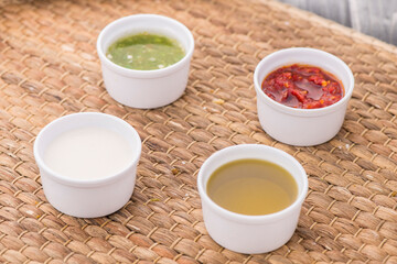 Assorted sauces of green seaddoning, red, chili, sweet, basil, paste and spicy served in dish isolated on table side view of arabic food