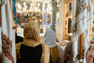 Two women are standing in the church, their heads are covered with scarves.