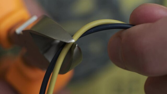 Pliers tool cutting red electric wire closeup on black background, service and repairing concept. cuts electrical wires with pliers, installation of household electrical appliances.