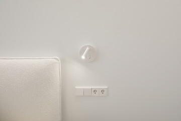 Bedside white LED wall lamp illuminating. Creative modern wall light source in bedroom. White...