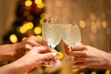 Hands of young people clinking with glass of champagne to celebrate and toasting with happiness in holiday