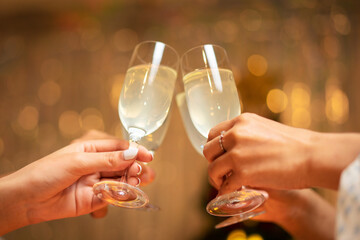 Hands of young people clinking with glass of champagne to celebrate and toasting with happiness in holiday