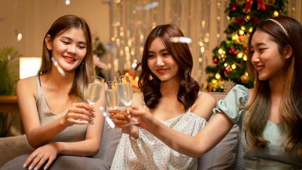 Young beautiful people sitting on the couch and clinking glass of champagne to toasting with happiness