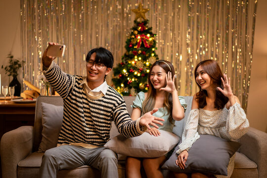 Young people sitting on the couch to smiling with enjoying and using smartphone to selfie together