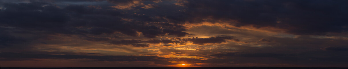 Landscape with bloody sunset. Panorama. Tragic gloomy sky. The last flashes of the sun on the storm...