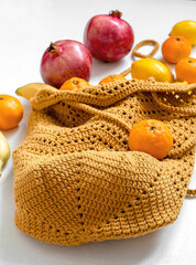 Crochet yellow mesh bag with fresh organic fruits on a yellow background. Eco friendly shoping and healthy eating concept.