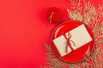 Christmas table setting with a festive gift box in red and gold colors. New Year background