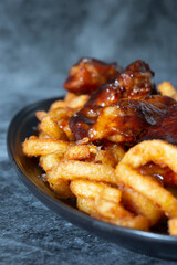 Pork belly covered in a spicy barbecue sauce on curly fries, seasoned with sea salt