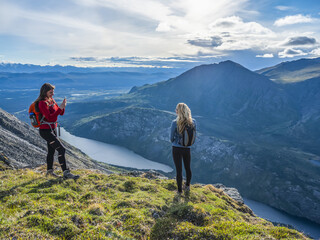 Two women exploring the mountains and wilderness of the Yukon, feeling alive and vibrant in the beautiful scenery around Haines Junction. One friend taking photos of the other one; Yukon, Canada