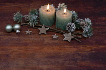 Green candles with Christmas decorations on old wooden floor with space for text.