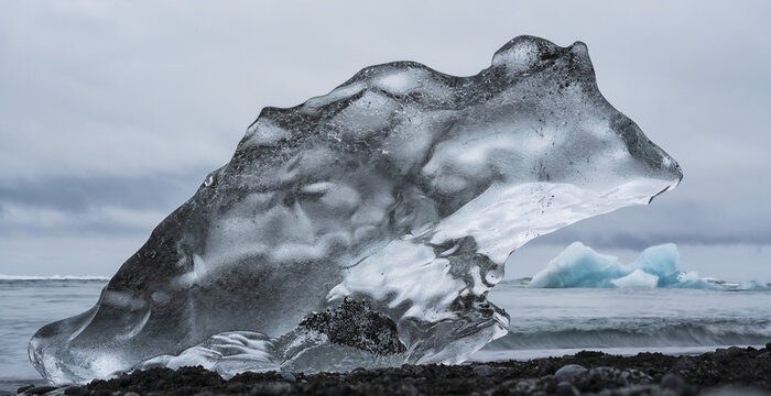 Piece of ice on Diamond Beach, near Jokusarlon, with the ocean behind it along the South coast of Iceland; Iceland