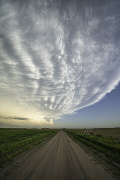 Dramatic skies over a dirt road and landscape seen during a storm chasing tour in the midwest of the United States; Kansas, United States of America
