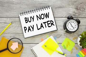 buy now pay later text on notepad business concept. alarm clock and notepad