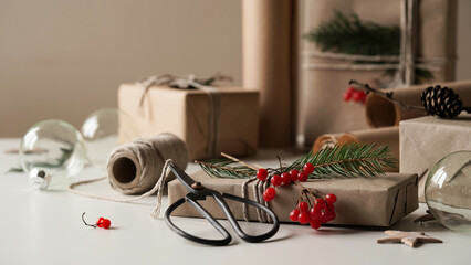 Zero waste and eco friendly christmas concept.Christmas and New Year gifts for family and friends wrapped in brown paper,rope and natural plant decor,tree branches,cones,berries,stars.Selective focus.
