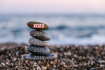 Pyramid of pebbles on the beach at sunset. Concept of the zen and happy new year 2023, stability,...