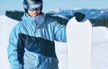 Snowboarder Of Man At Ski Resort On The Background Blue Sky,  Hold Snowboard. Wearing Ski Glasses....